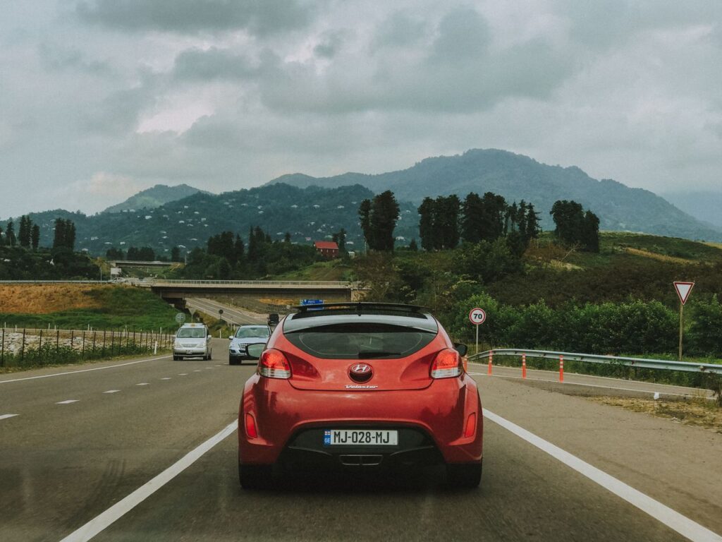 Mastering the First Impression: Your intriguing post title goes here Red Hyundai Veloster travels on a scenic highway in Georgia with lush mountains in the background.